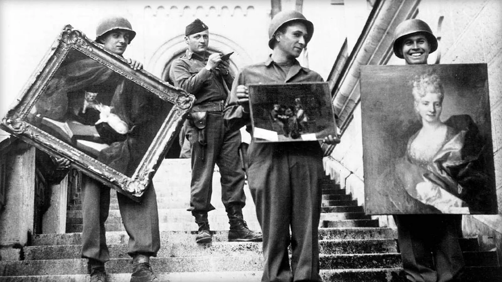 Four American soldiers on the stone steps of Neuschwanstein Castle, three holding framed paintings, one of them a portrait of a woman, while an officer behind them takes notes.